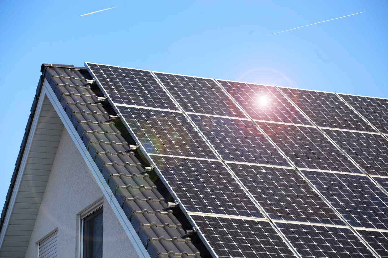 Einfamilienhaus mit dachintegrierter Photovoltaikanlage bei blauem Himmel