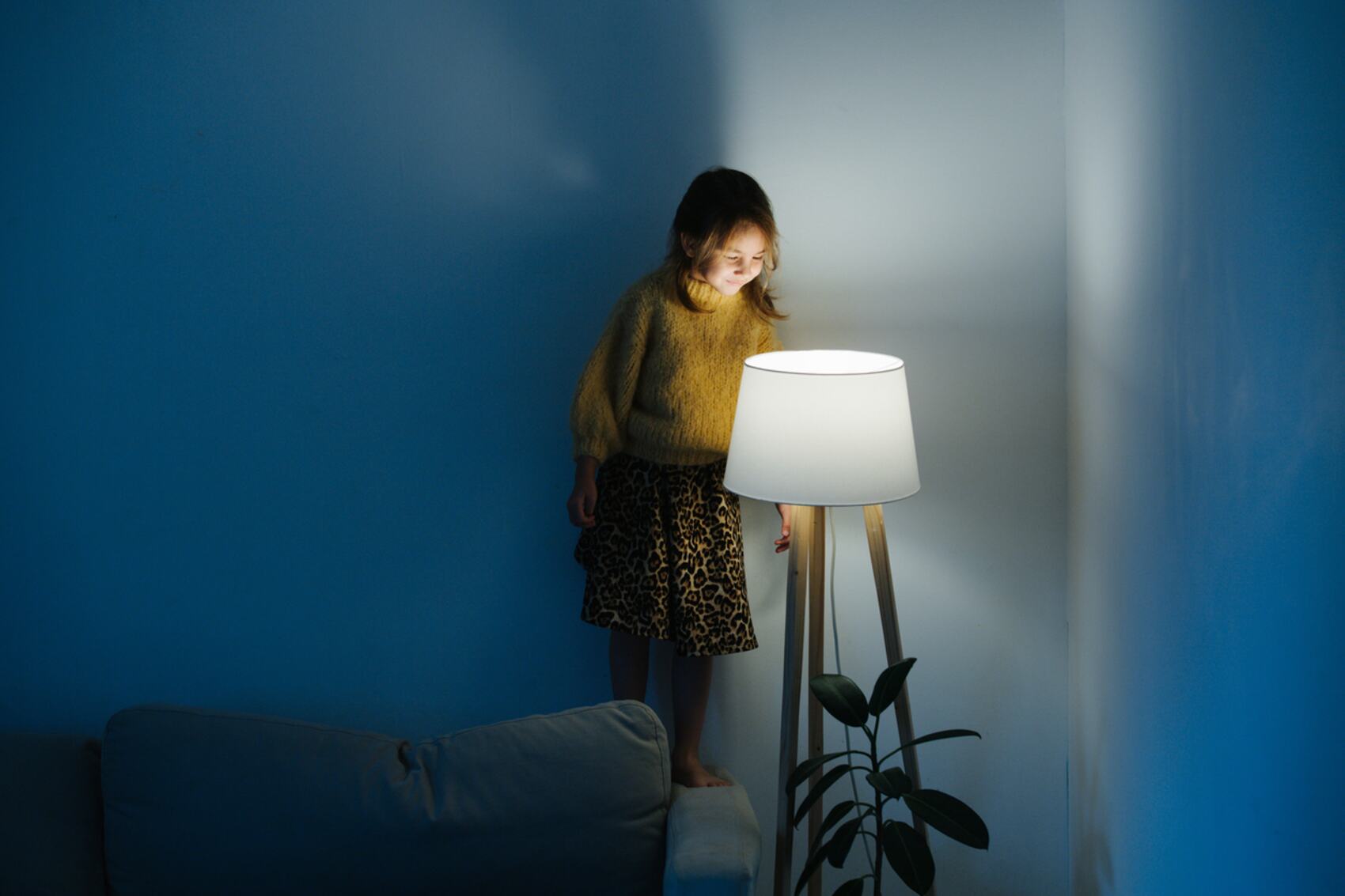 Kind schaltet zuhause zufrieden eine Stehlampe ein